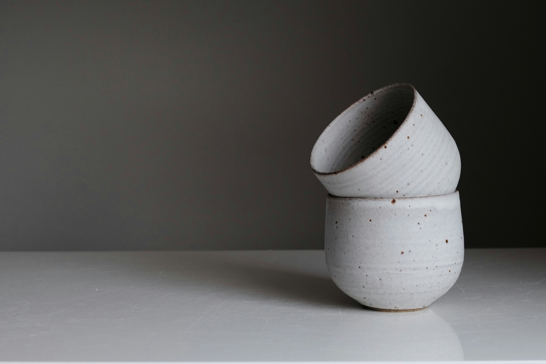 Two white ceramic vessels on a light table